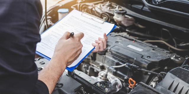 Reparador de mecânico de automóveis verificação de motor de carro com inspeção escrevendo na área de transferência a lista de verificação de máquina de reparo, serviço e manutenção de automóveis