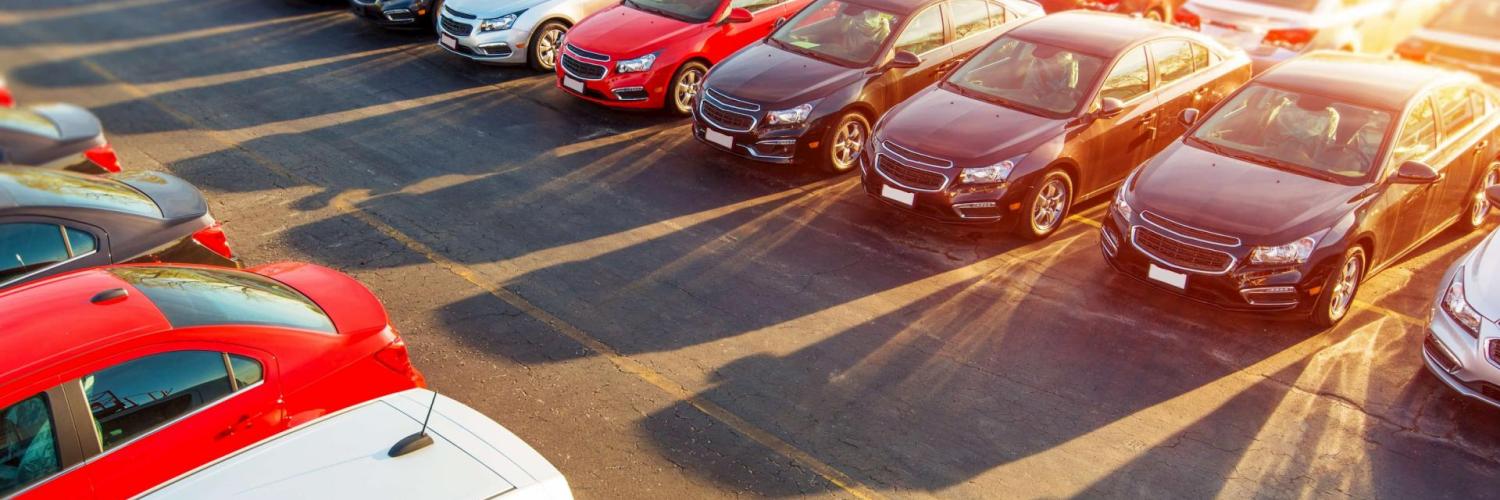 Estacionamento com uma série de carros estacionados com o sol ao fundo